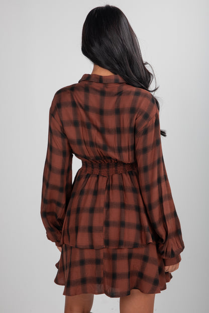 Woman wearing a brown and black plaid dress on a white background