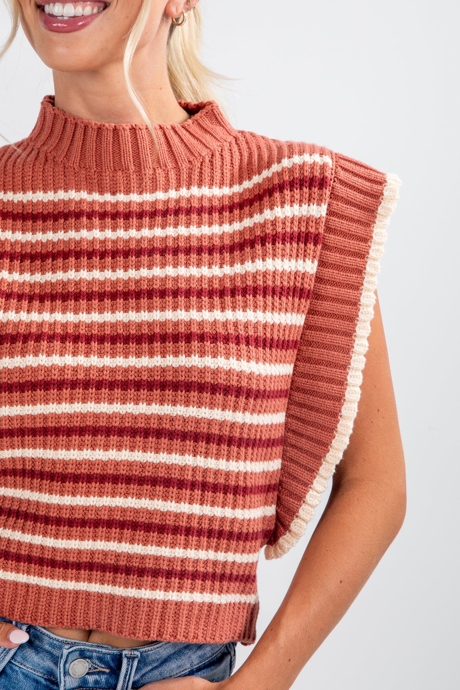 Woman wearing a striped sweater with fringes on a white background