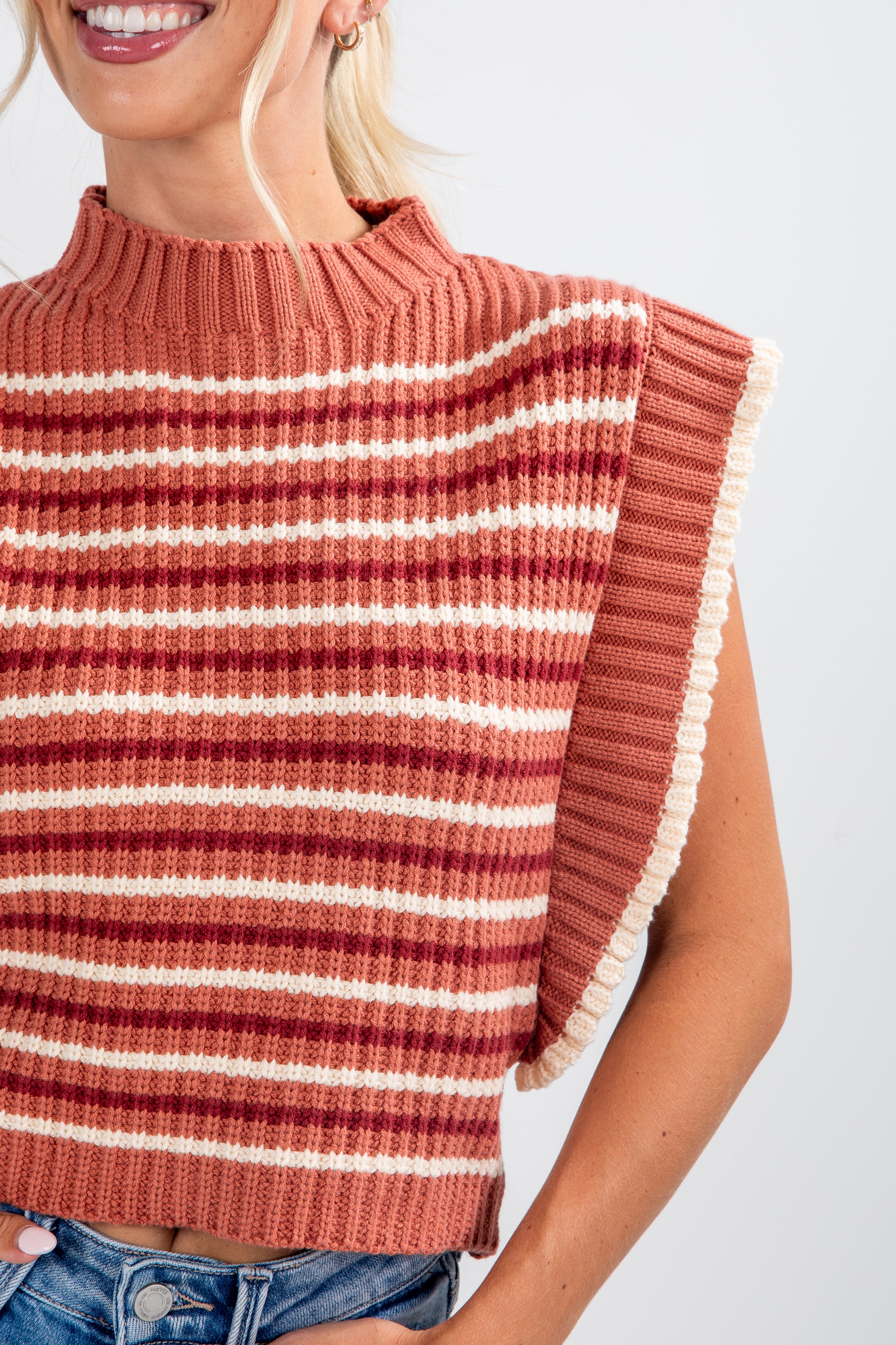 Woman wearing a striped sweater with fringes on a white background