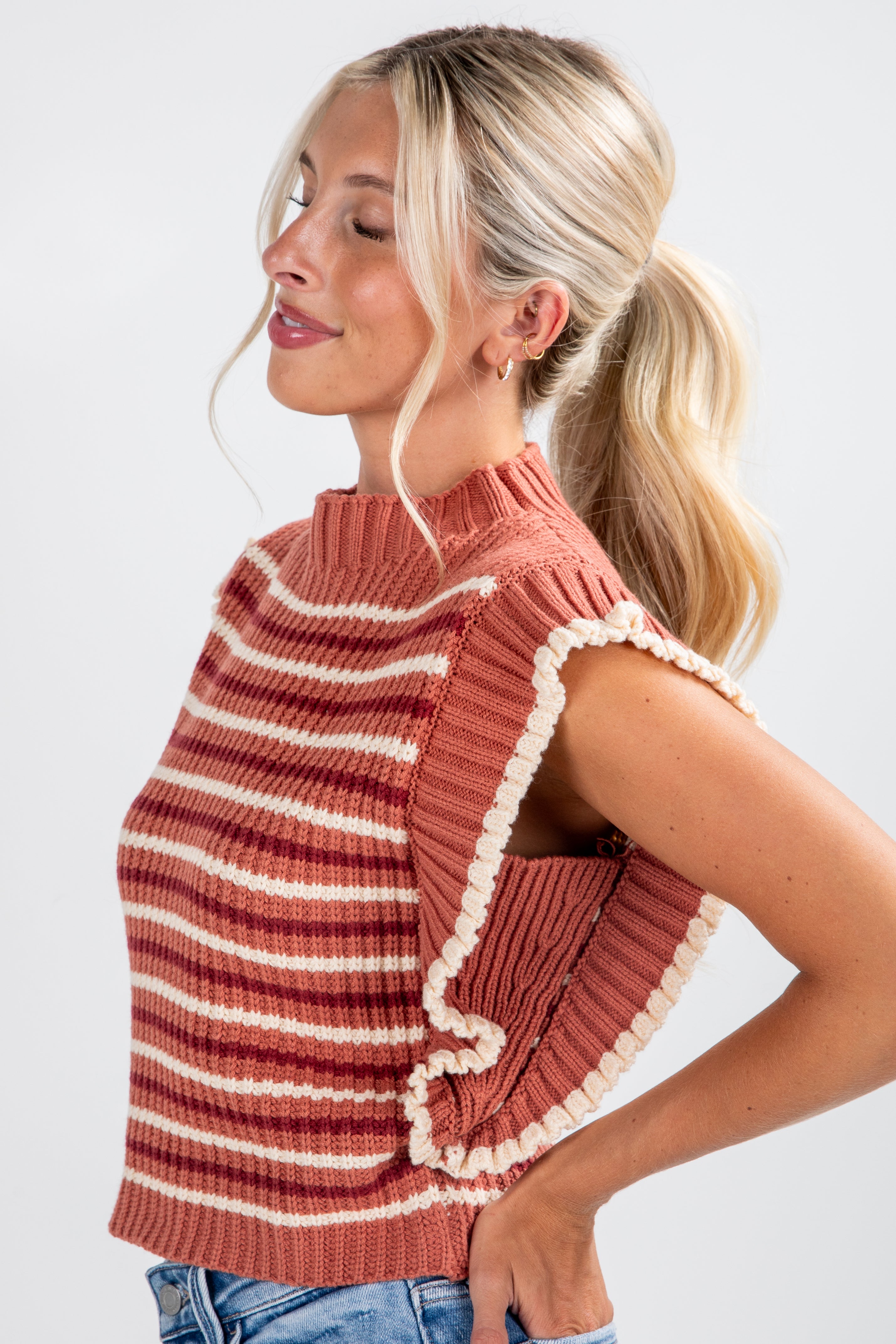 Woman wearing a striped sweater with ruffled edges on a white background