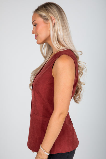 Woman wearing a red sleeveless top against a plain background