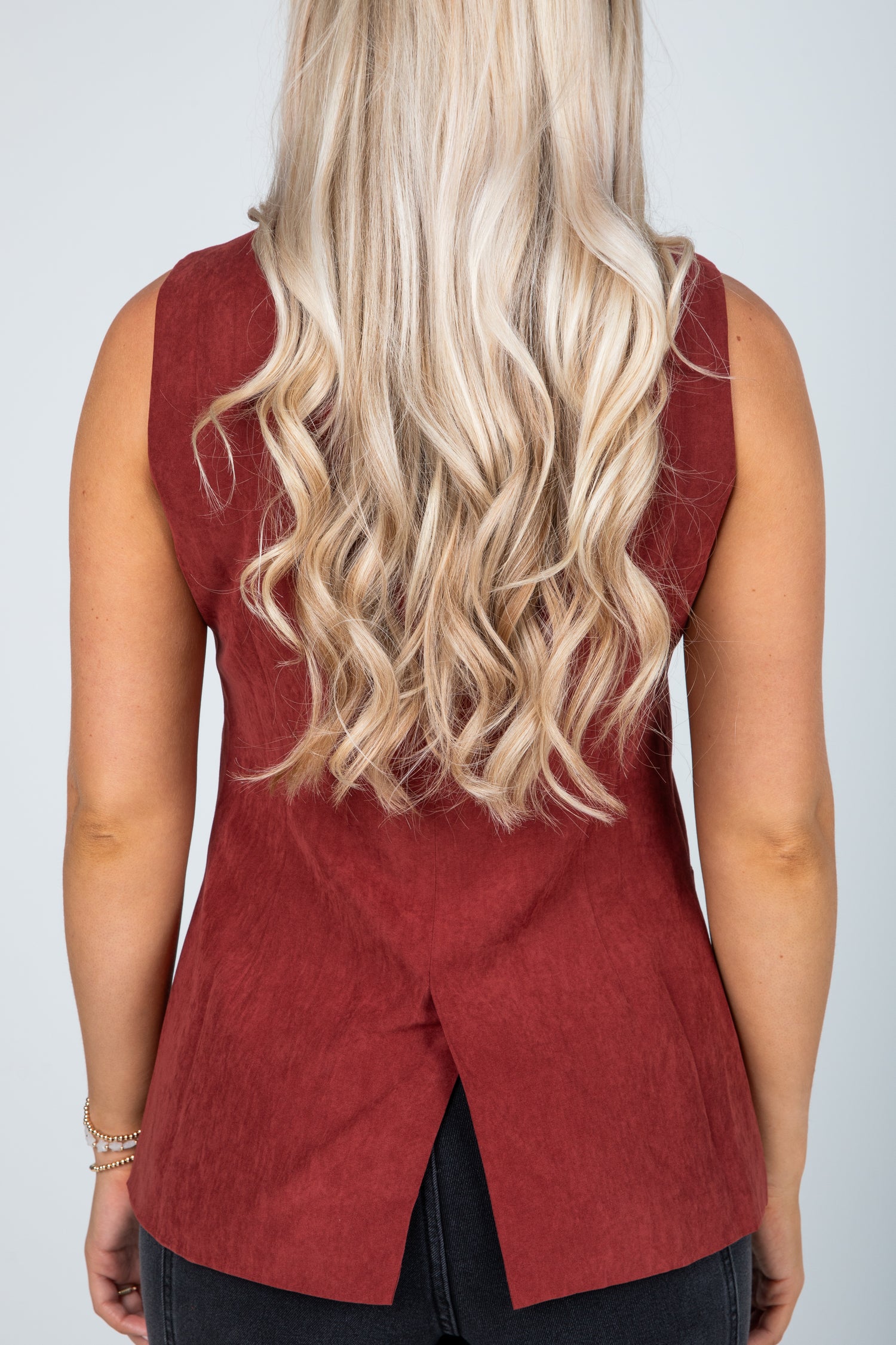 Person wearing a red sleeveless top with a plain background