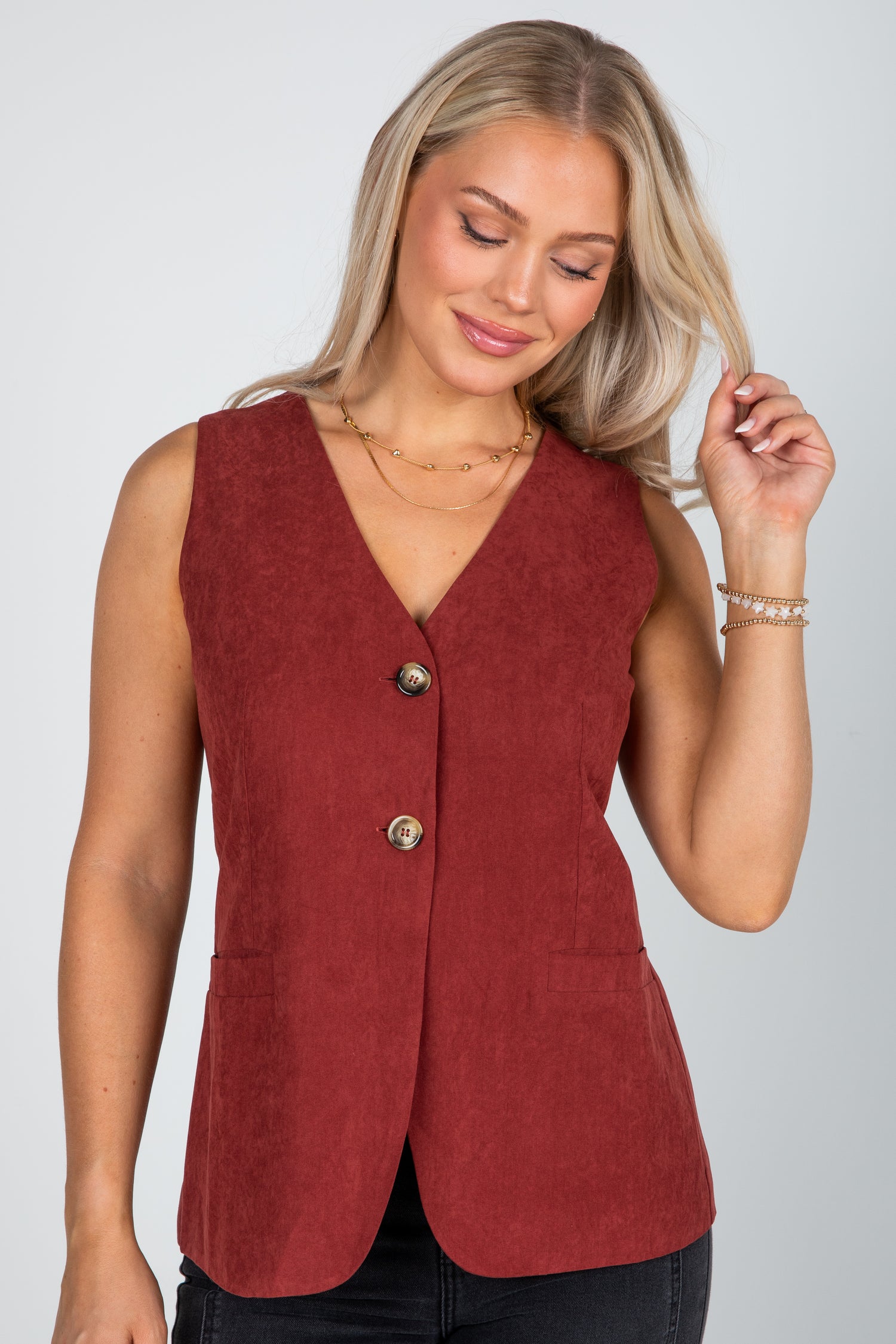 Woman wearing a red vest with buttons on a plain background