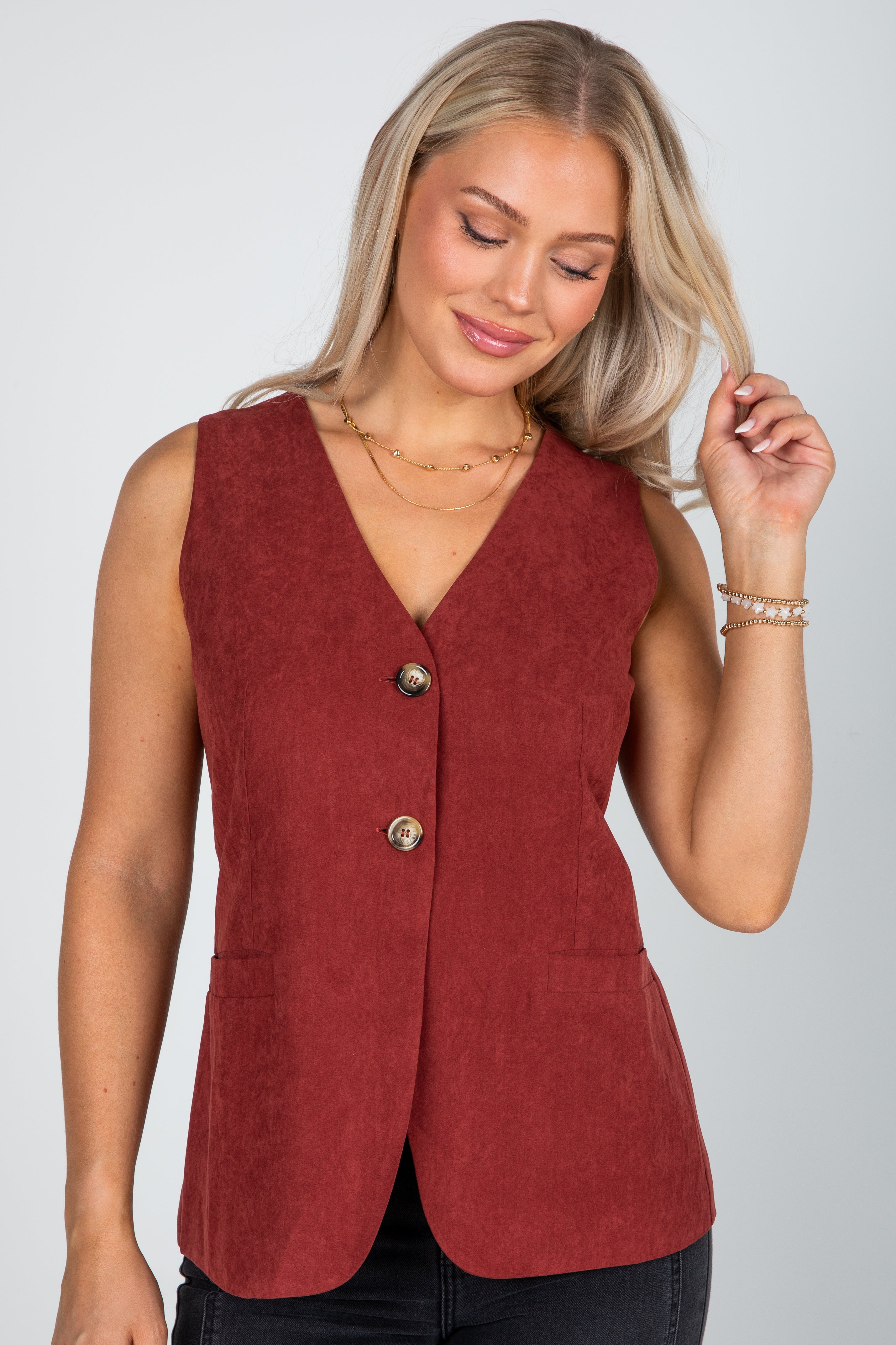 Woman wearing a red vest with buttons on a plain background