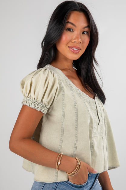 Woman wearing a light green blouse with short sleeves against a white background