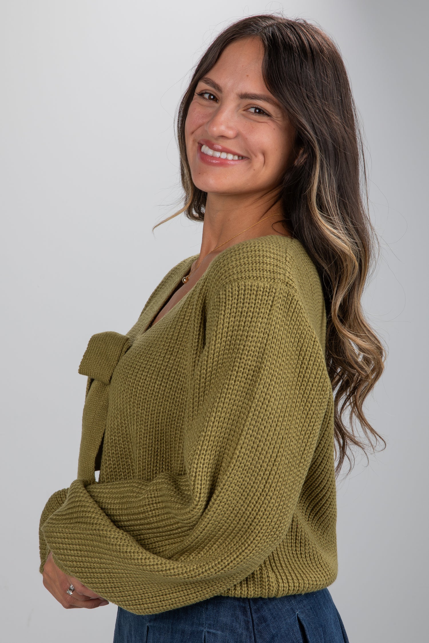 Woman wearing a green knitted sweater against a plain background