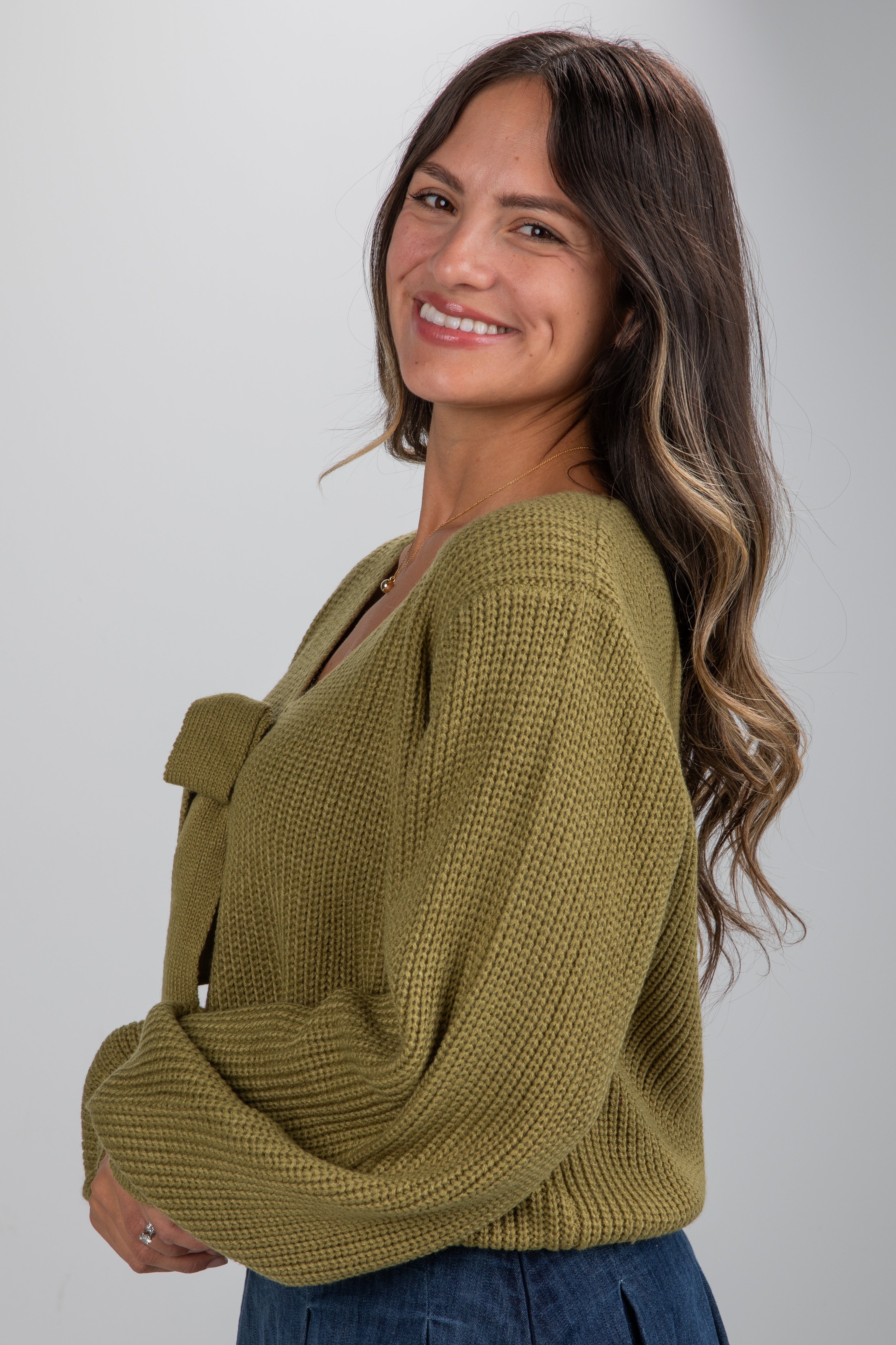 Woman wearing a green knitted sweater against a plain background