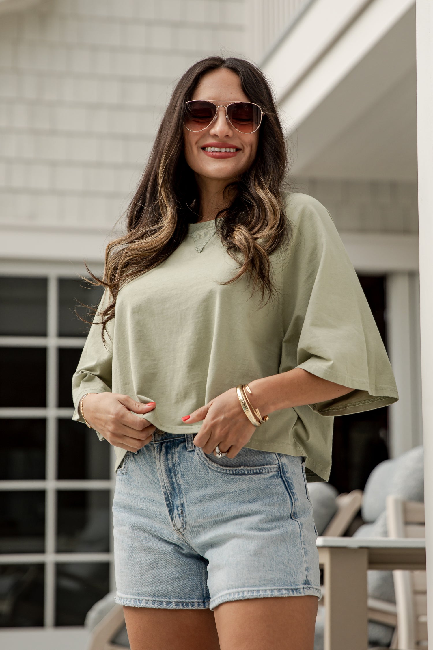 Woman wearing a light green top and denim shorts outdoors.