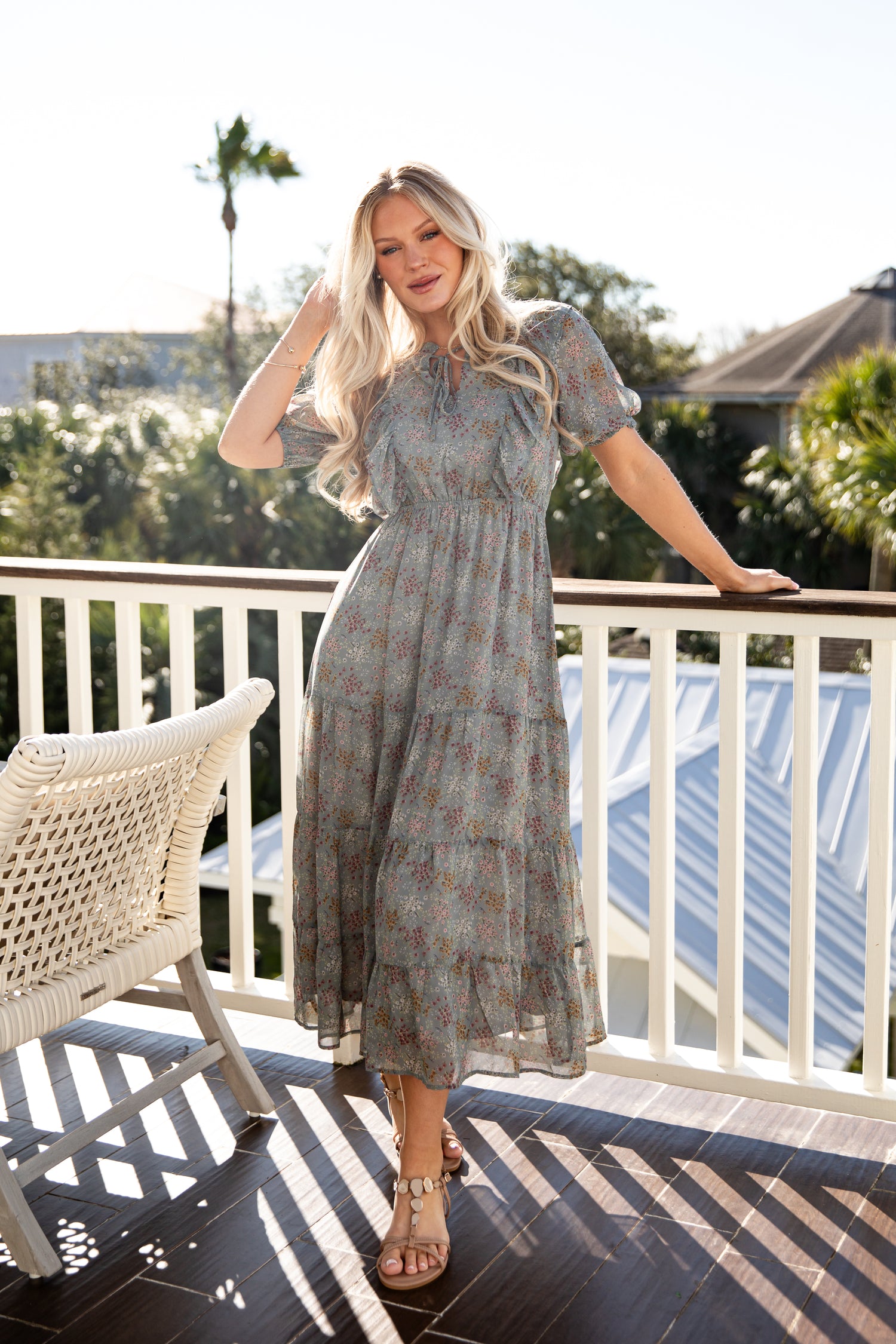 Woman in a patterned dress standing on a balcony with a scenic background