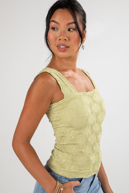 Woman wearing a light green sleeveless top against a white background