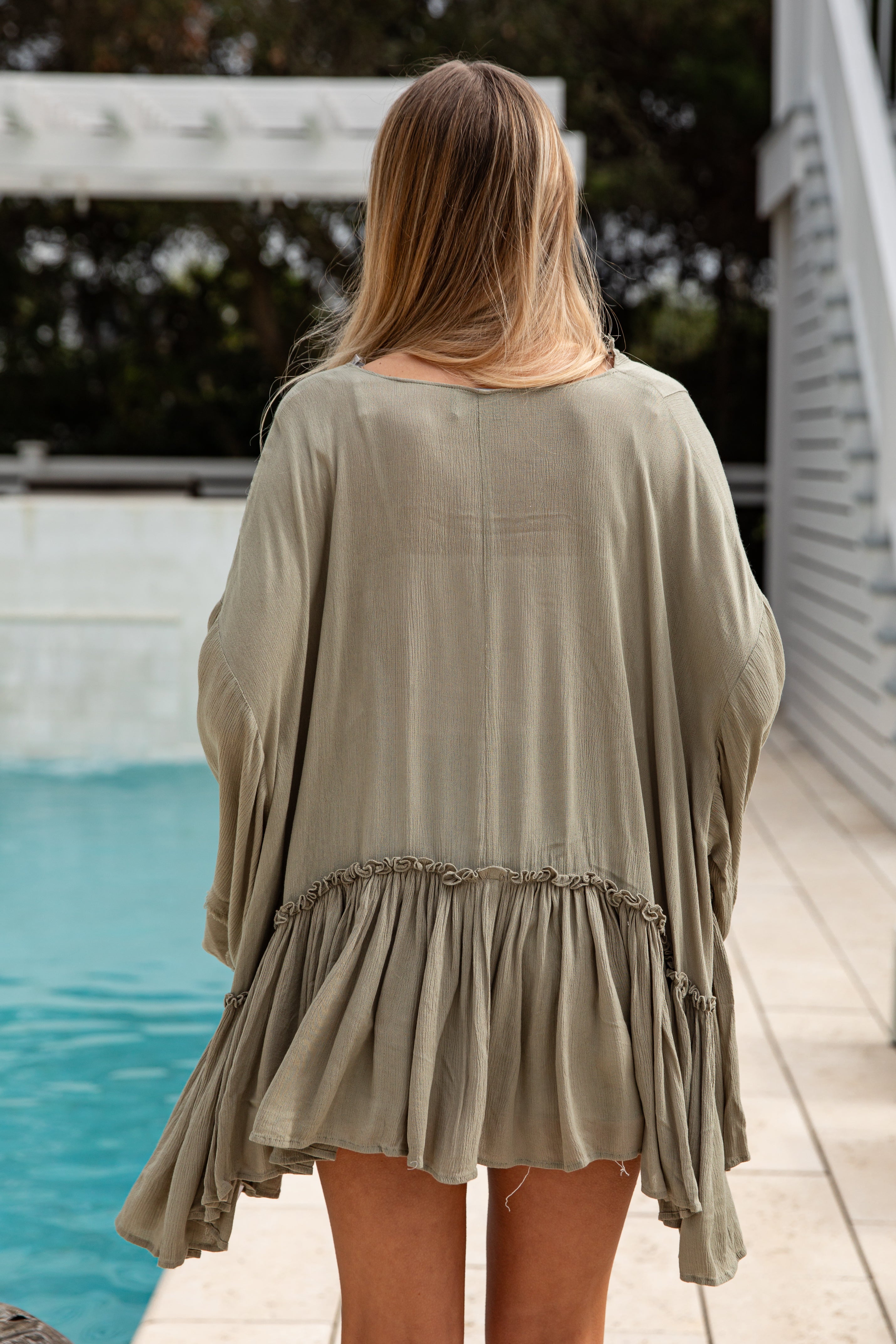 Woman wearing a light green dress by a poolside