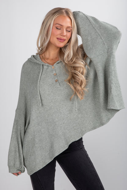 Woman wearing a gray hooded sweater against a white background