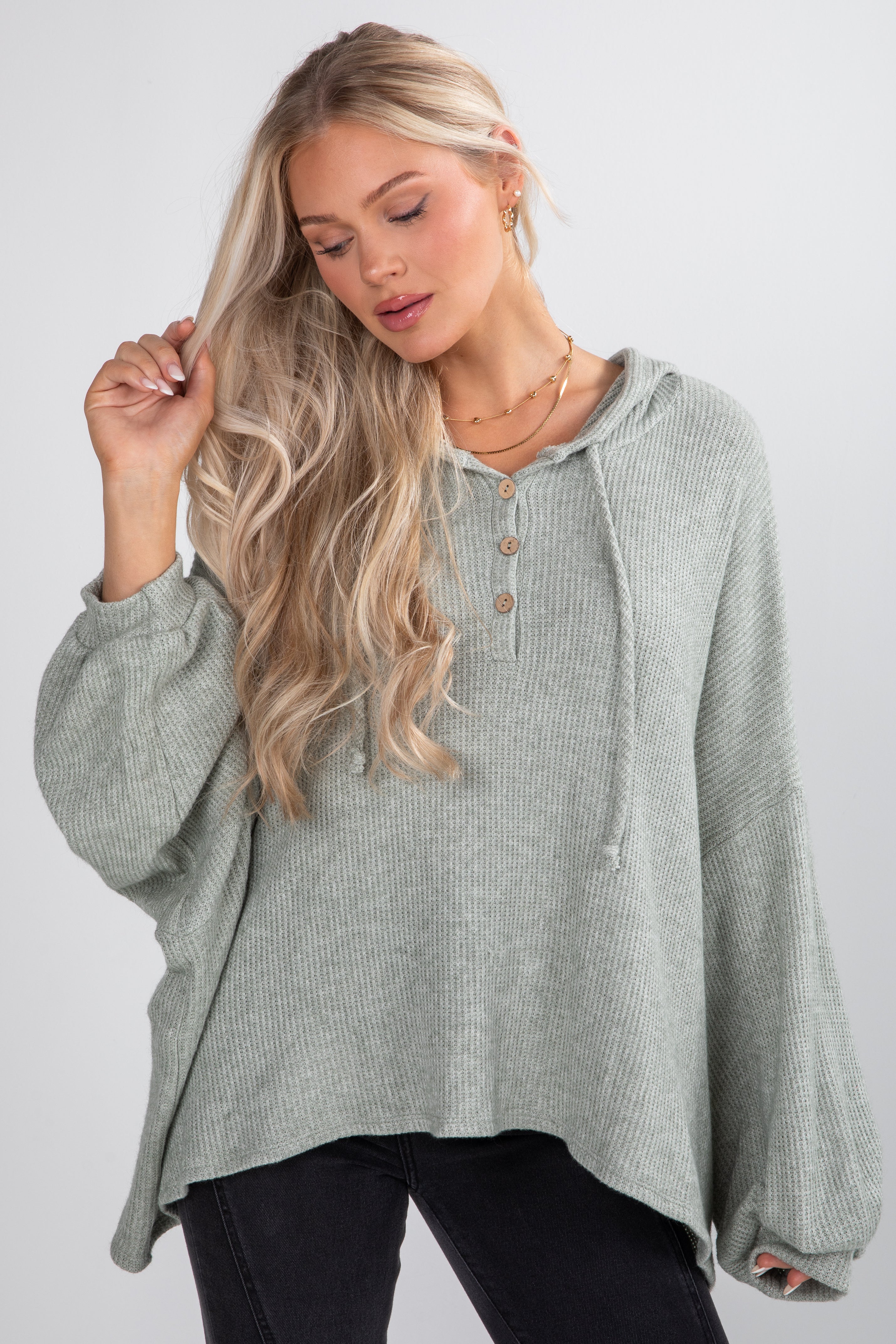 Woman wearing a light gray hooded top with a plain background