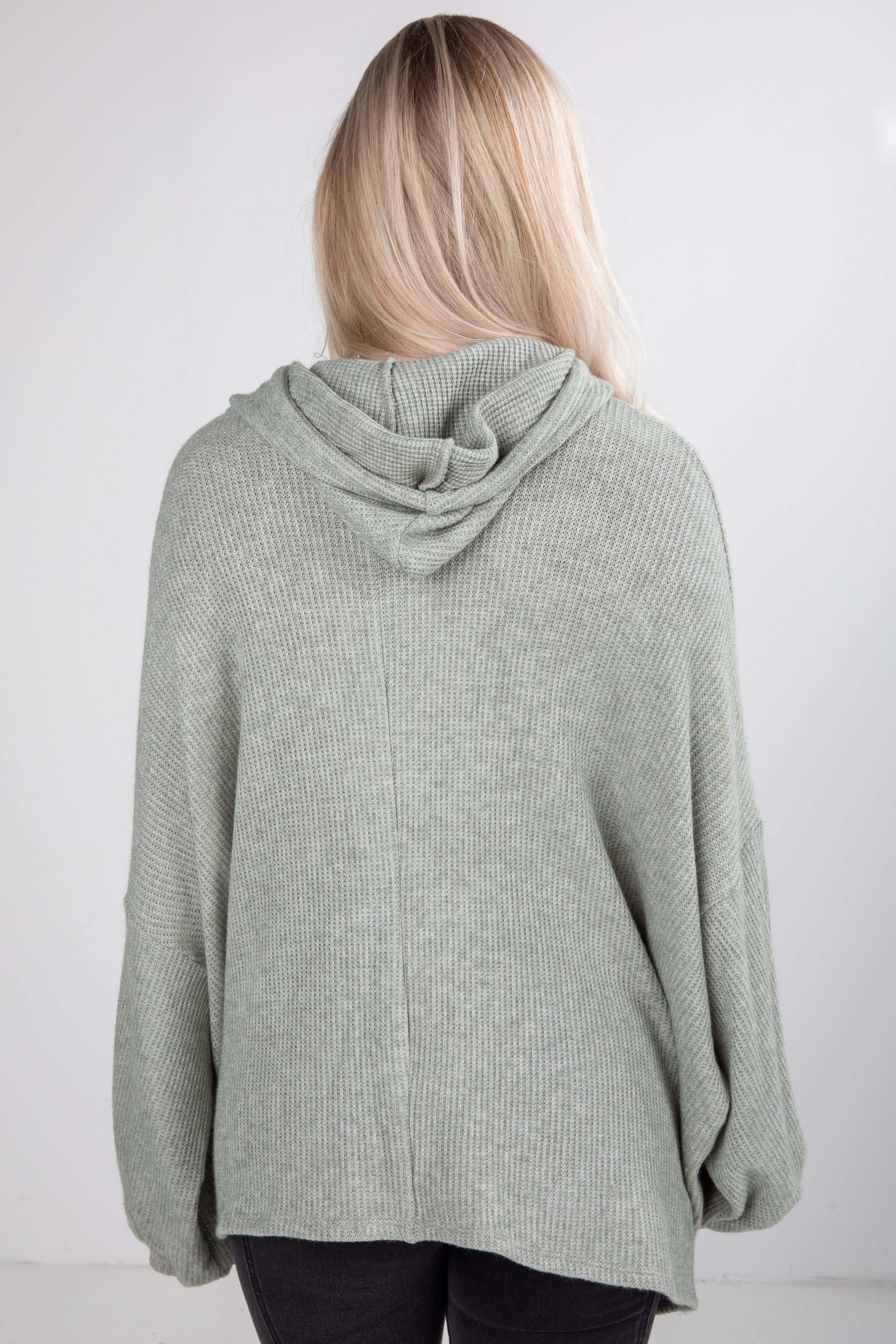 Person wearing a gray hooded sweater against a white background