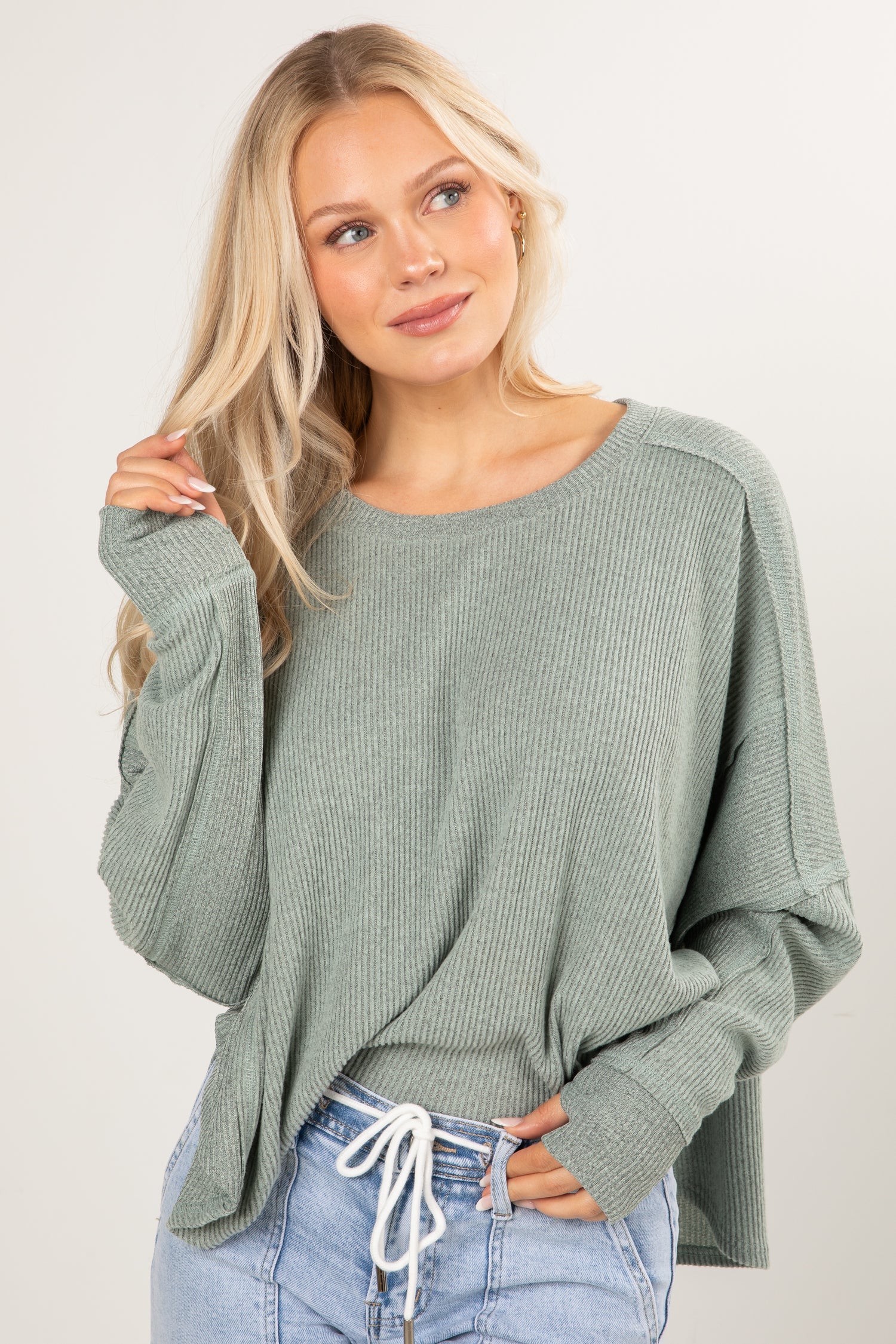 Woman wearing a green sweater and blue jeans on a white background
