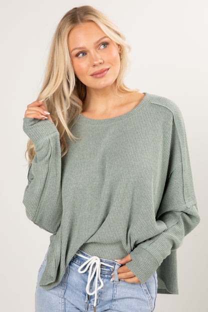 Woman wearing a green sweater and blue jeans on a white background