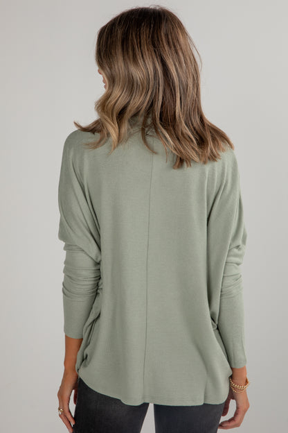 Person wearing a light green long-sleeve top against a plain background