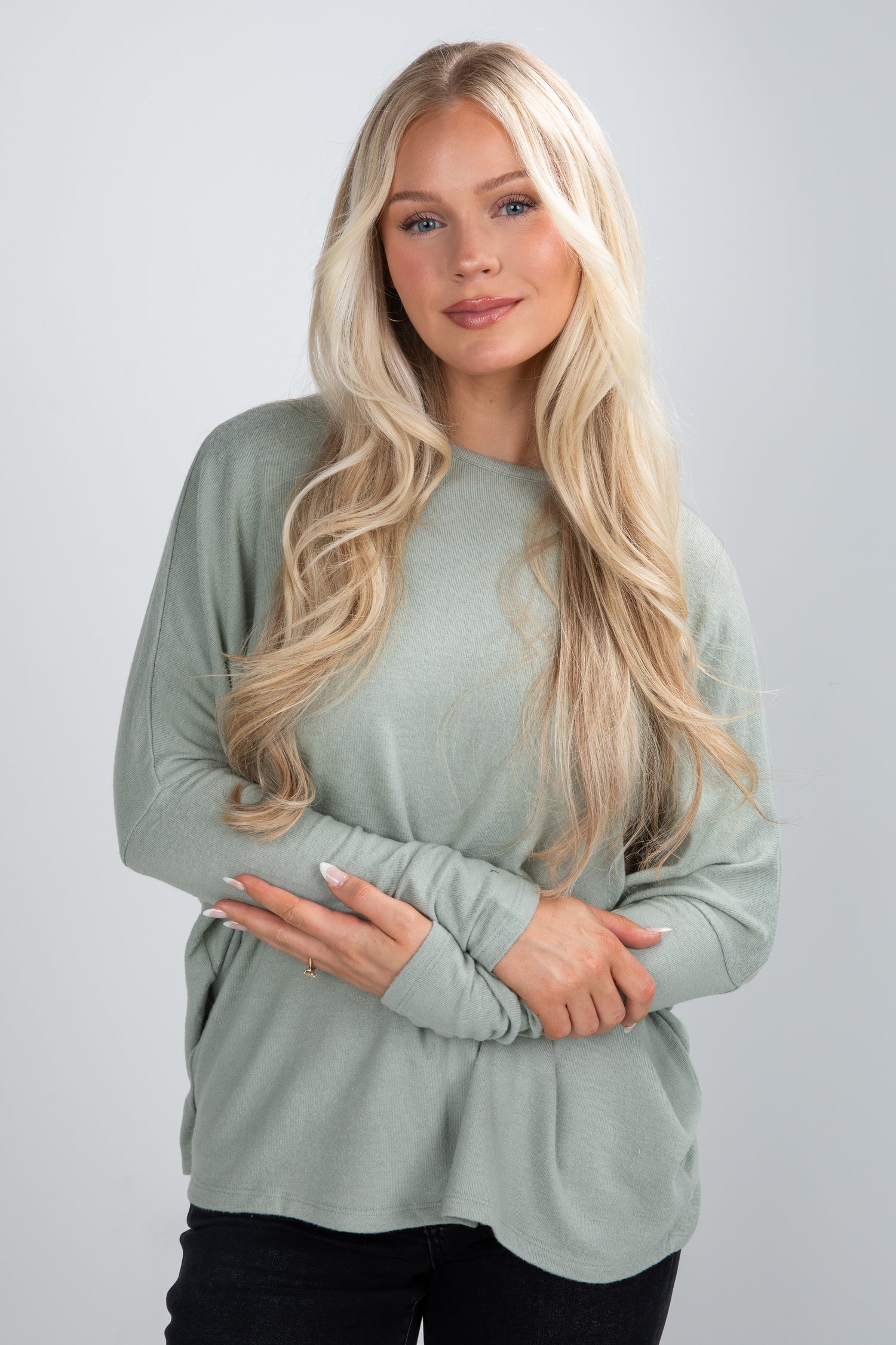 Woman wearing a light green long-sleeve top against a plain background