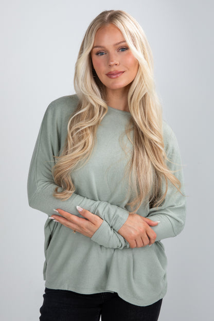 Woman wearing a light green long-sleeve top against a plain background