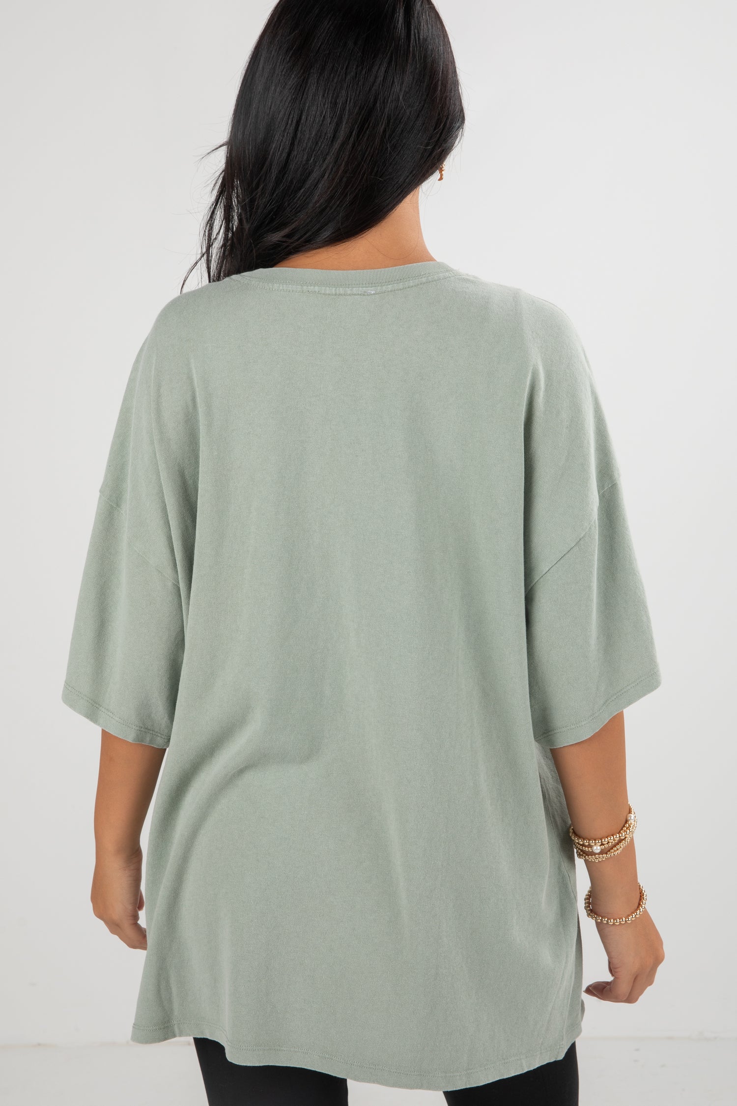 Person wearing a light green oversized t-shirt on a white background