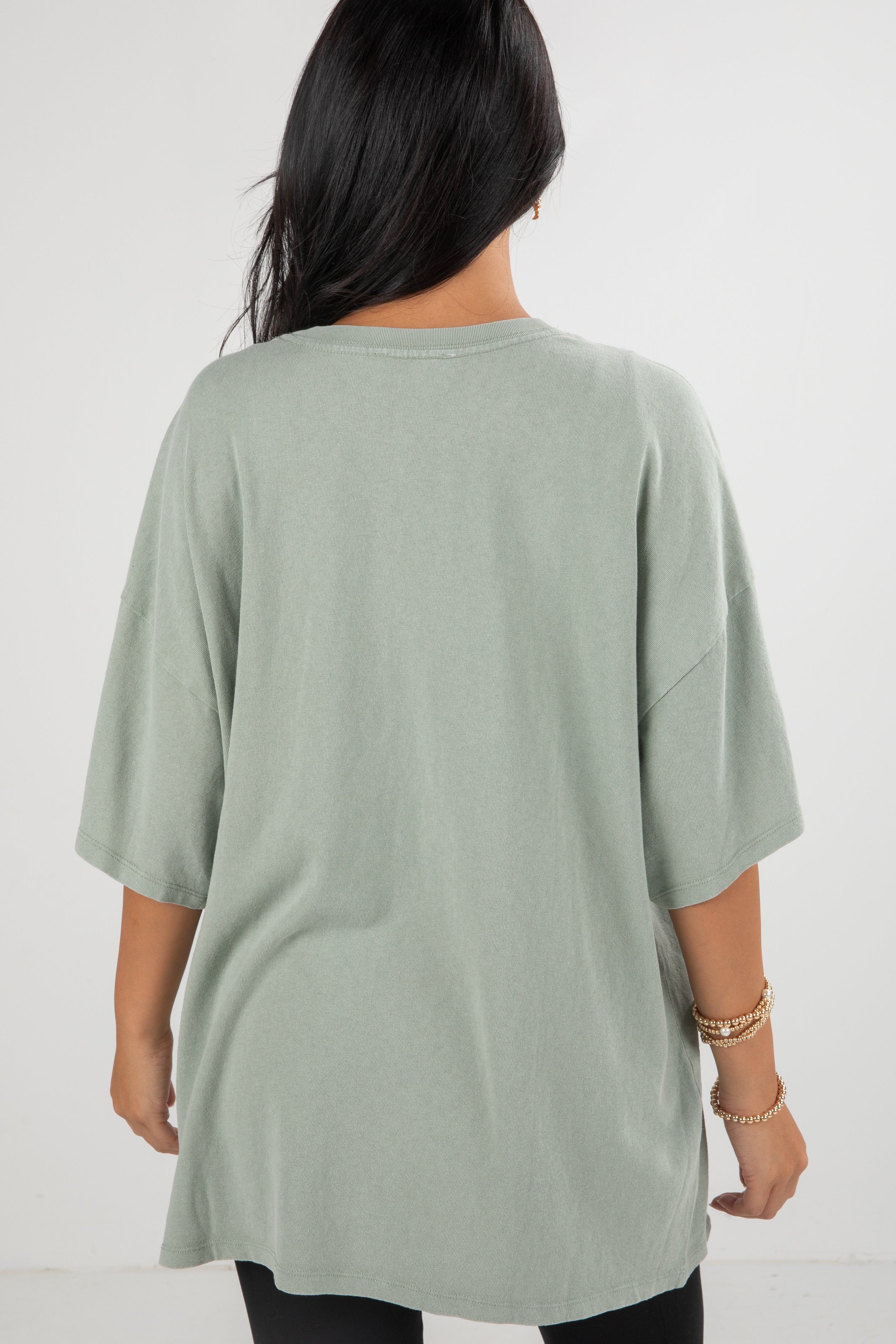 Person wearing a light green oversized t-shirt on a white background