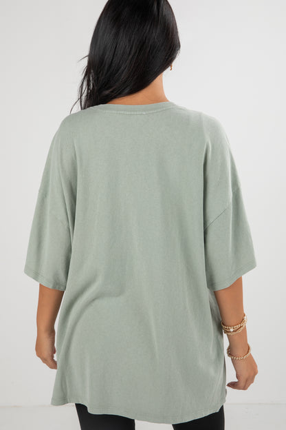Person wearing a light green oversized t-shirt on a white background