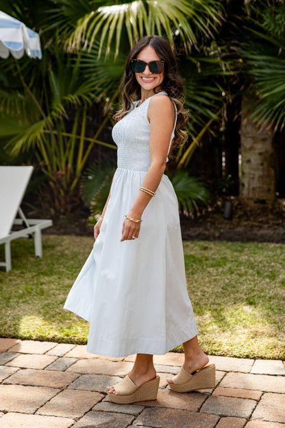 Woman in a white dress standing outdoors with palm trees in the background