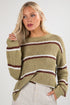 Woman wearing a green sweater with brown and white stripes on a plain background