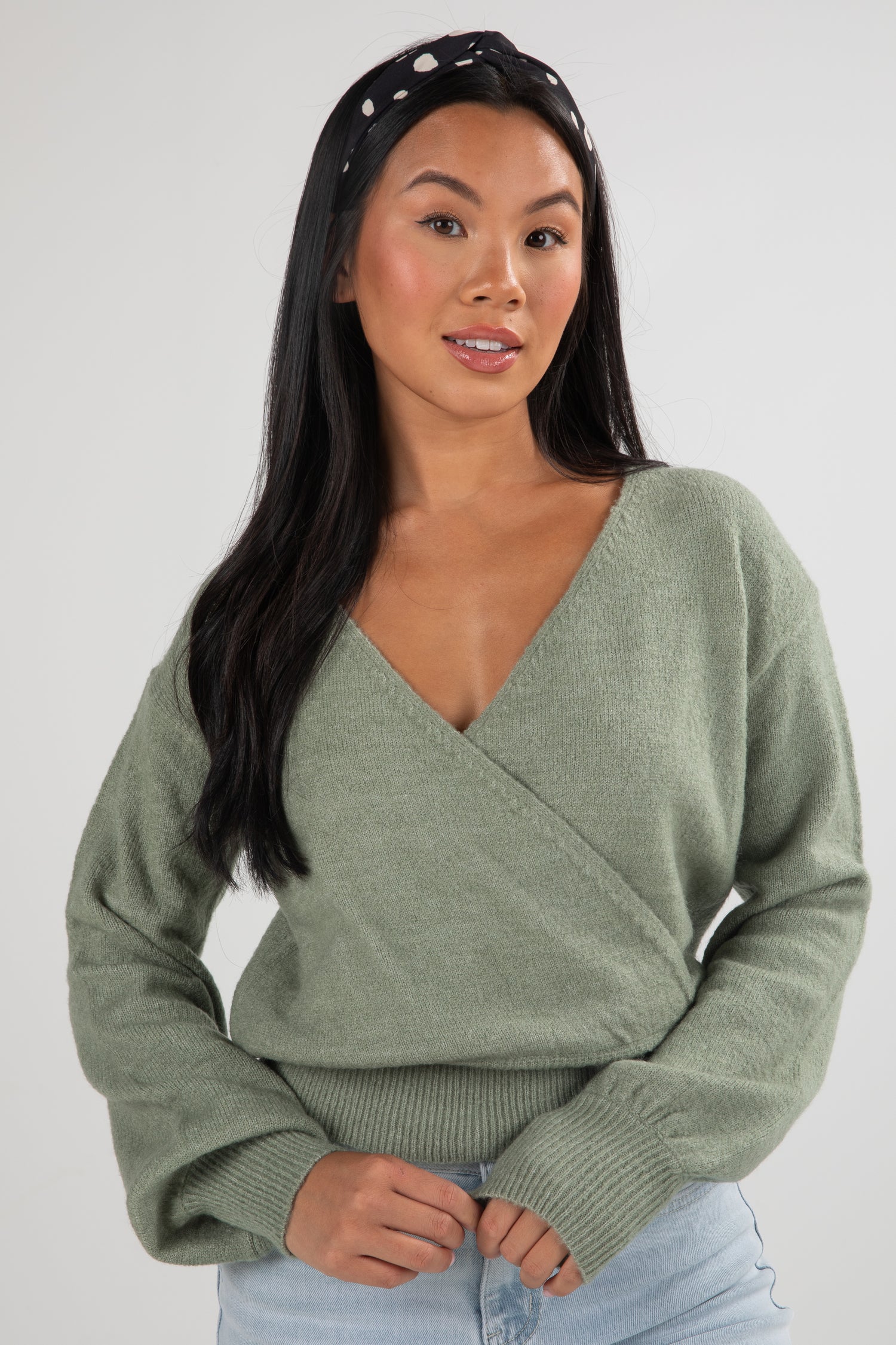 Woman wearing a green sweater against a plain background