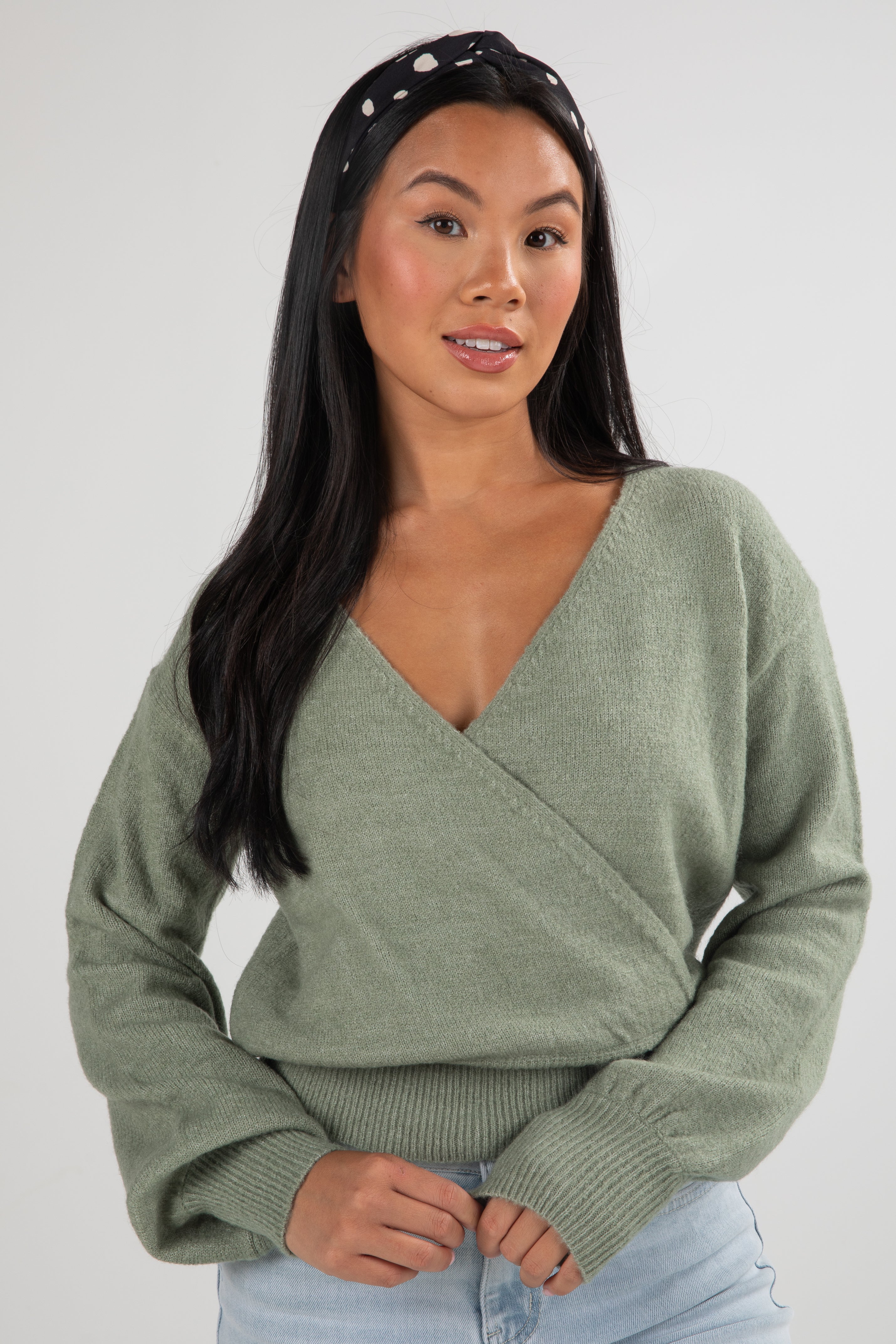 Woman wearing a green sweater against a plain background