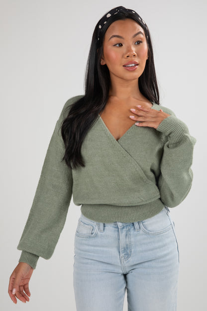 Woman wearing a green sweater and light blue jeans on a white background