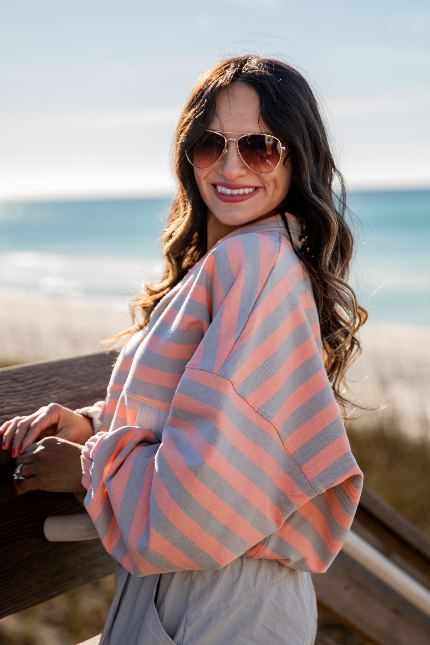 Woman wearing a striped sweater and sunglasses by the beach