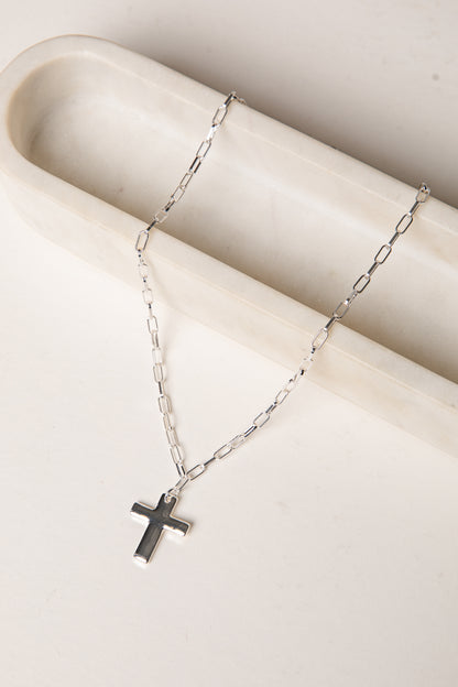 Silver necklace with a cross pendant on a white surface