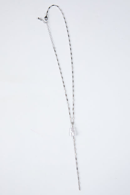 Silver necklace on a light gray background