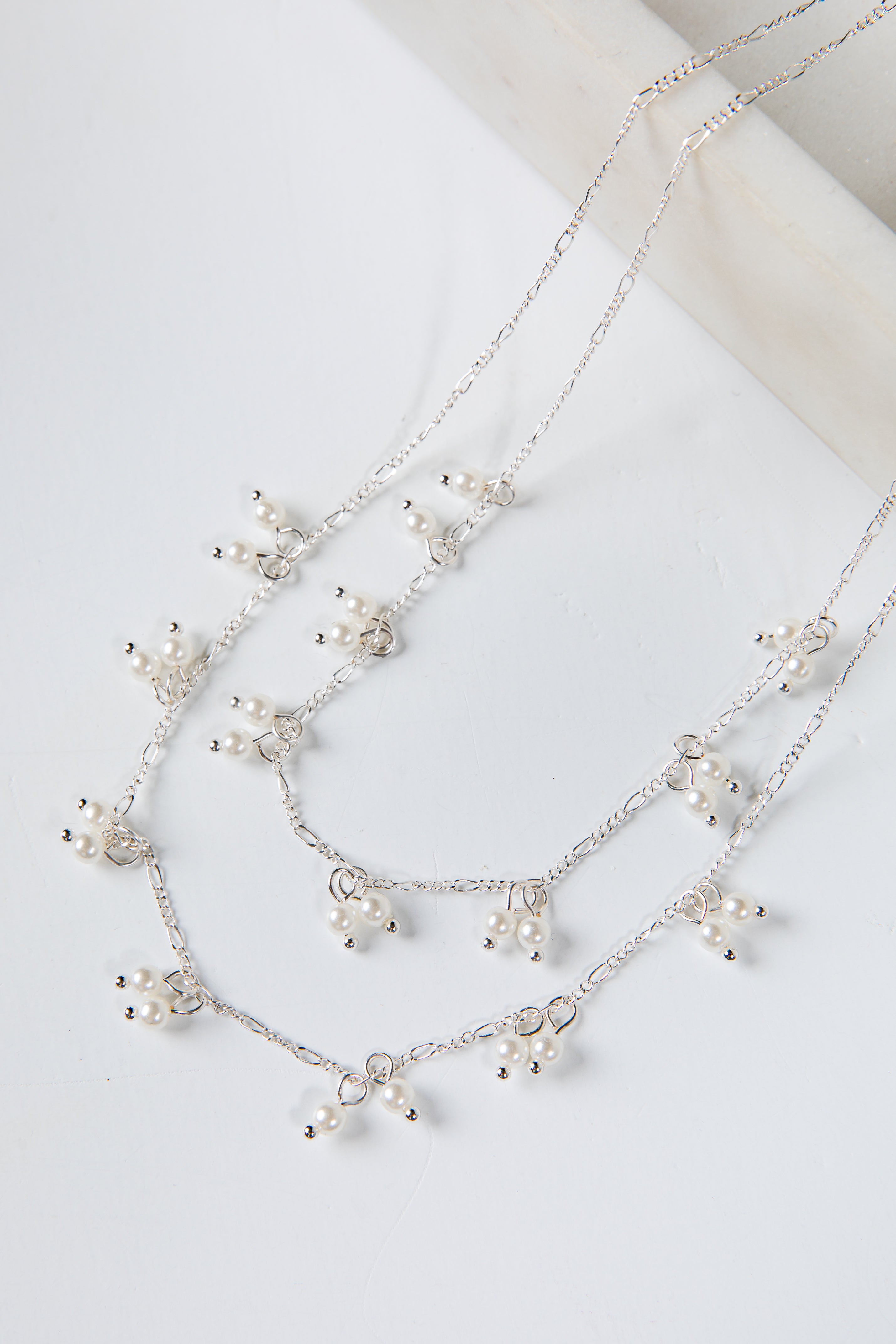 Silver necklace with small pearls on a light background