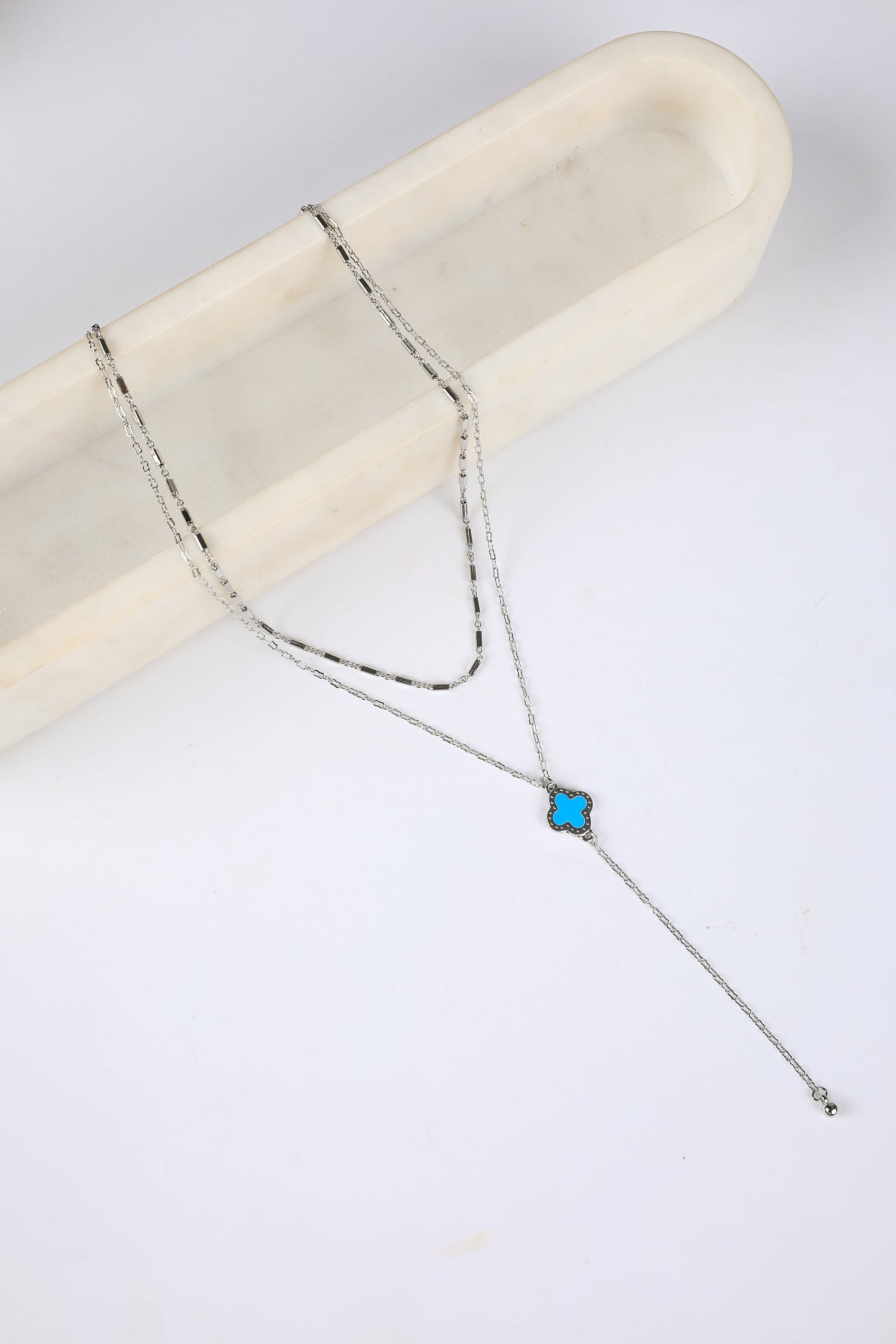 Silver necklace with a blue gemstone on a white background