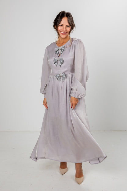 Woman wearing a light purple dress with floral embellishments on a white background