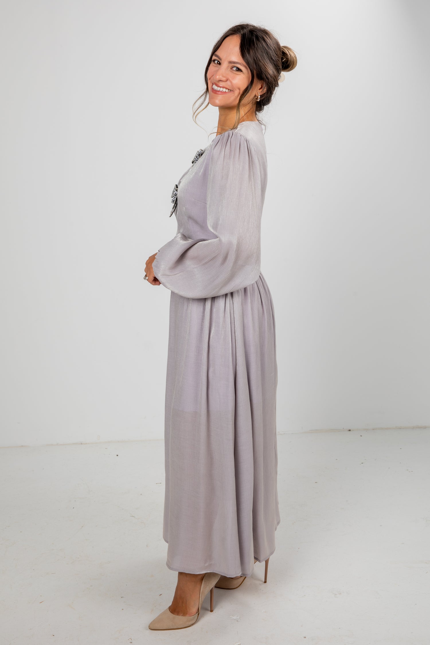 Woman wearing a long light gray dress against a white background