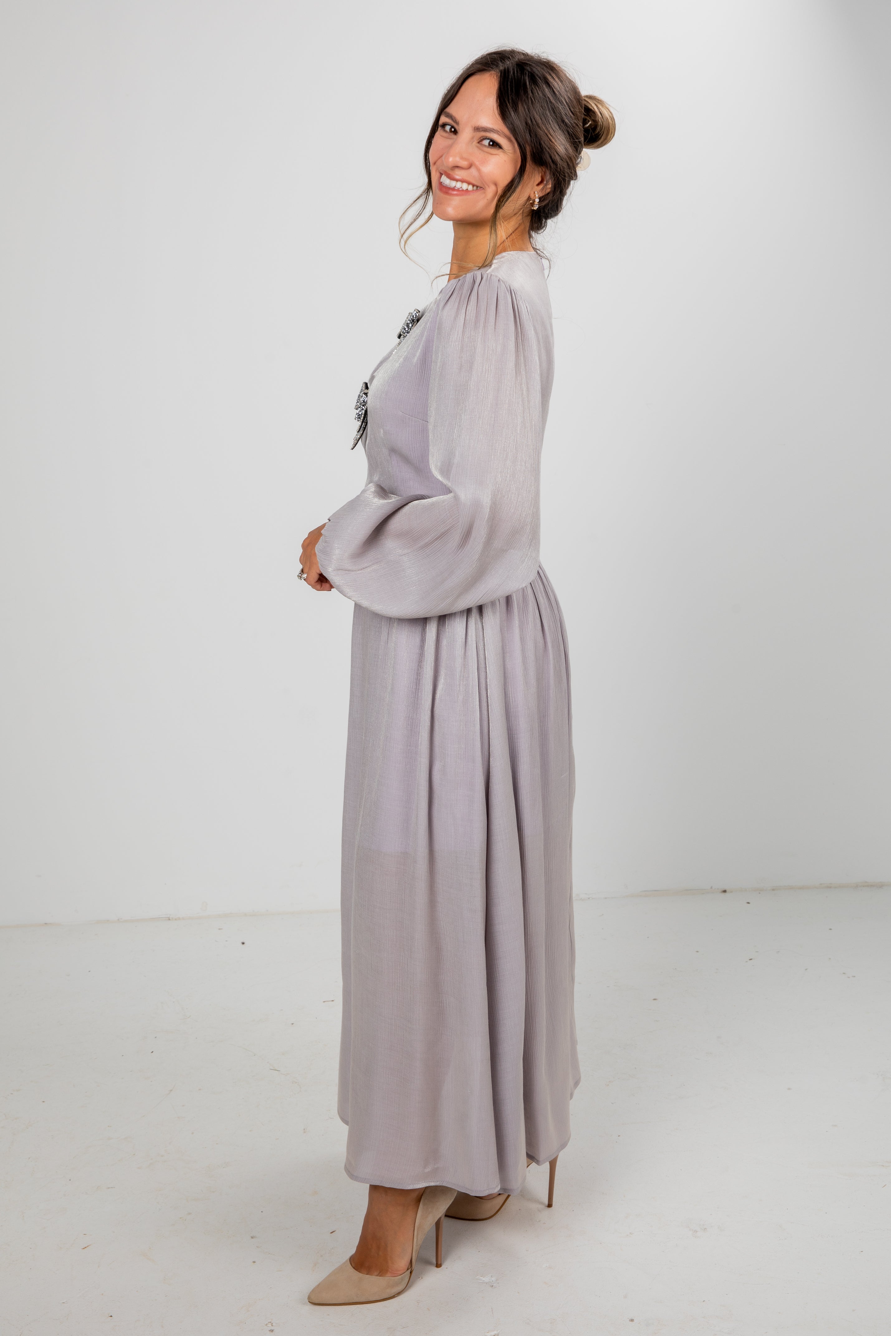 Woman wearing a long light gray dress against a white background