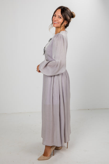 Woman wearing a long light gray dress against a white background