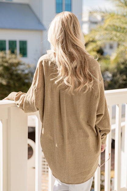 Person wearing a beige sweater standing on a balcony with a blurred background