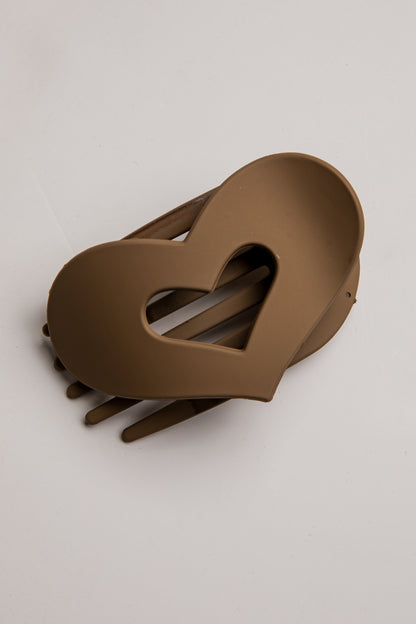 A heart-shaped hair claw clip in a matte taupe-brown color, shown on a clean off-white background.