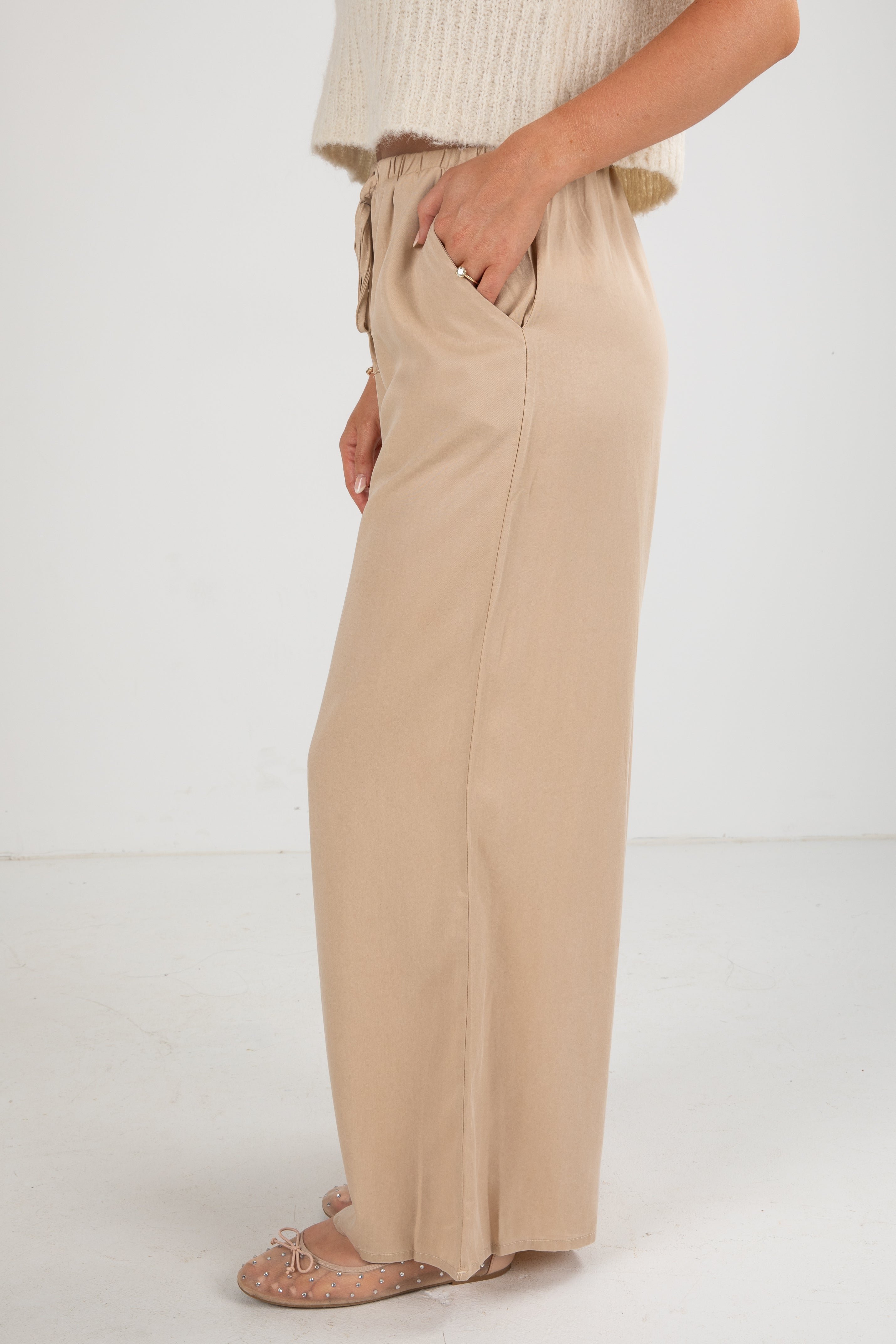 Beige wide-leg pants worn by a person on a white background