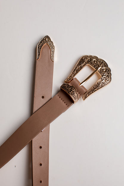 A light brown leather belt with an ornate, engraved bronze-toned buckle, laid out diagonally on a clean white background.