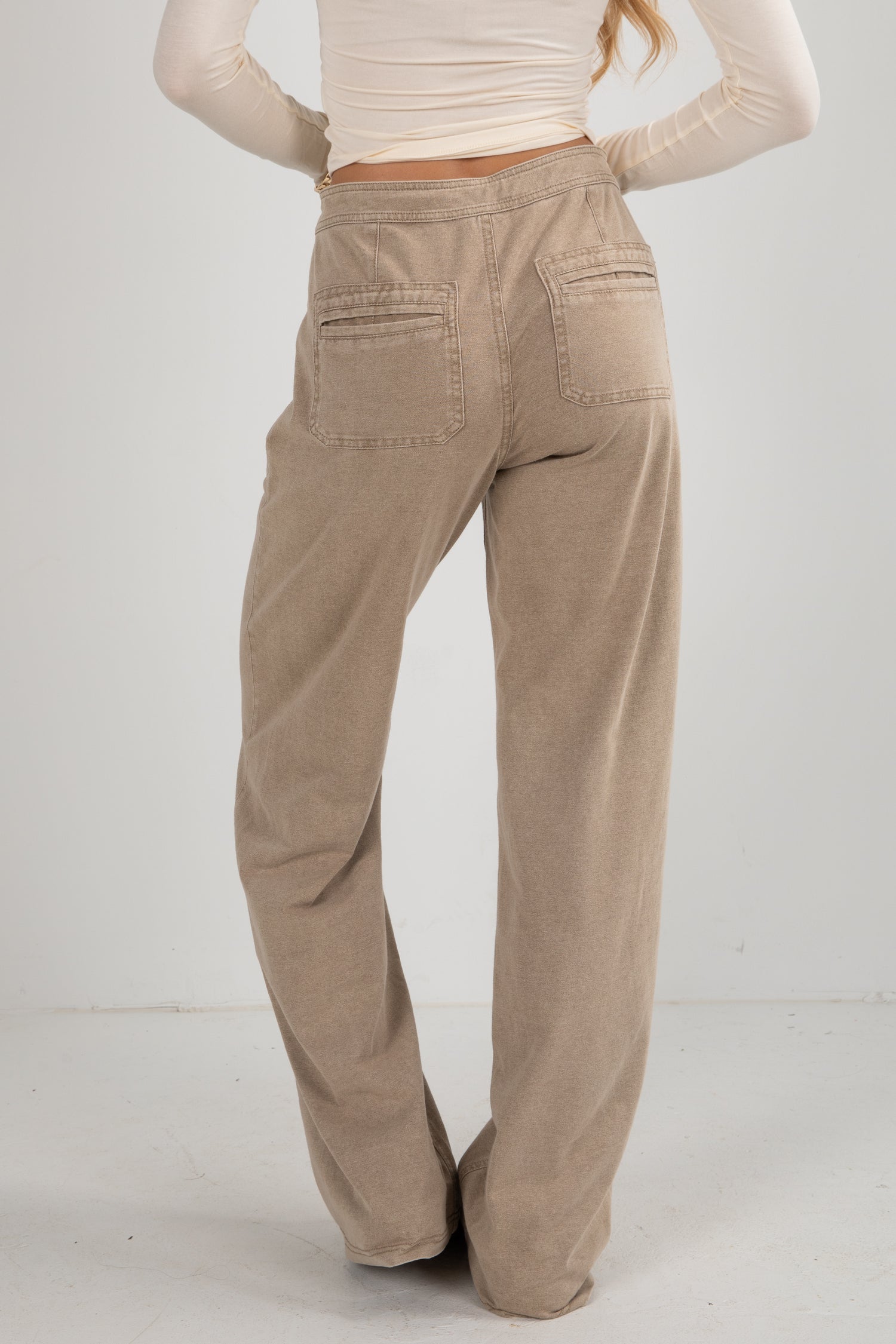 Beige corduroy pants worn by a person on a white background
