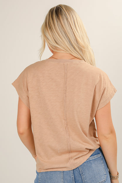 Person wearing a beige t-shirt and blue jeans on a plain background