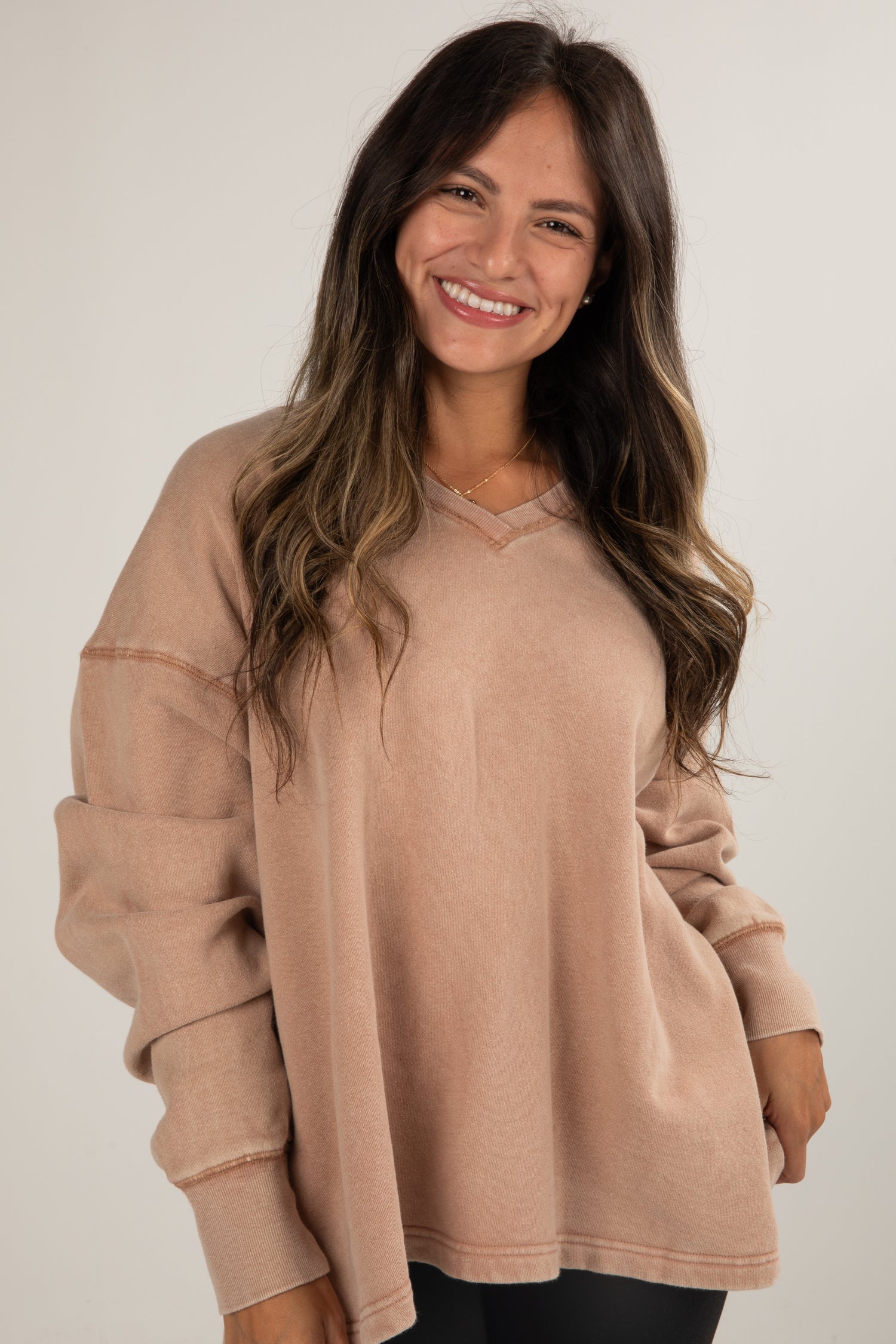 Woman wearing a beige sweater against a plain background