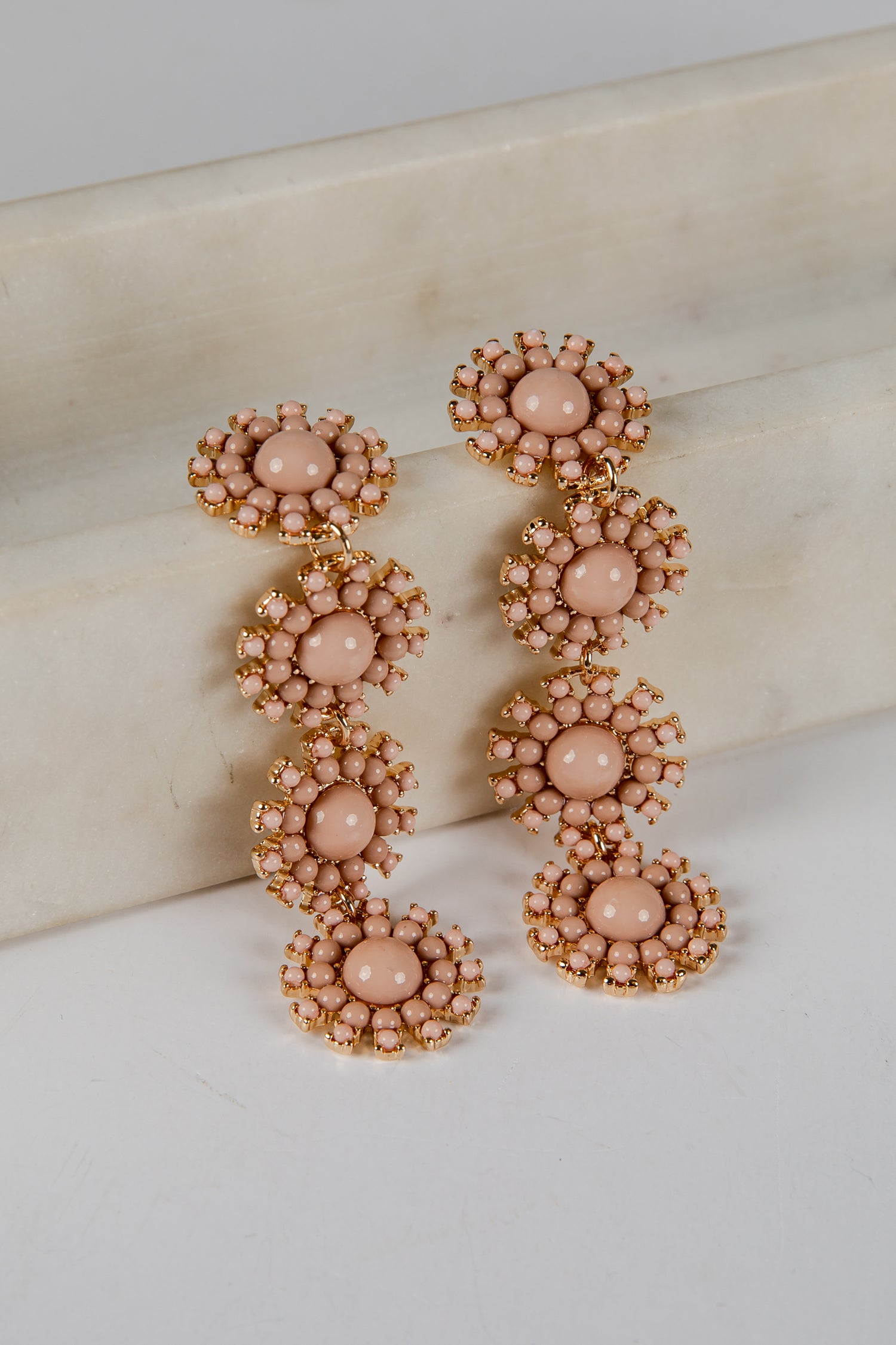 Pair of pink beaded earrings on a marble surface