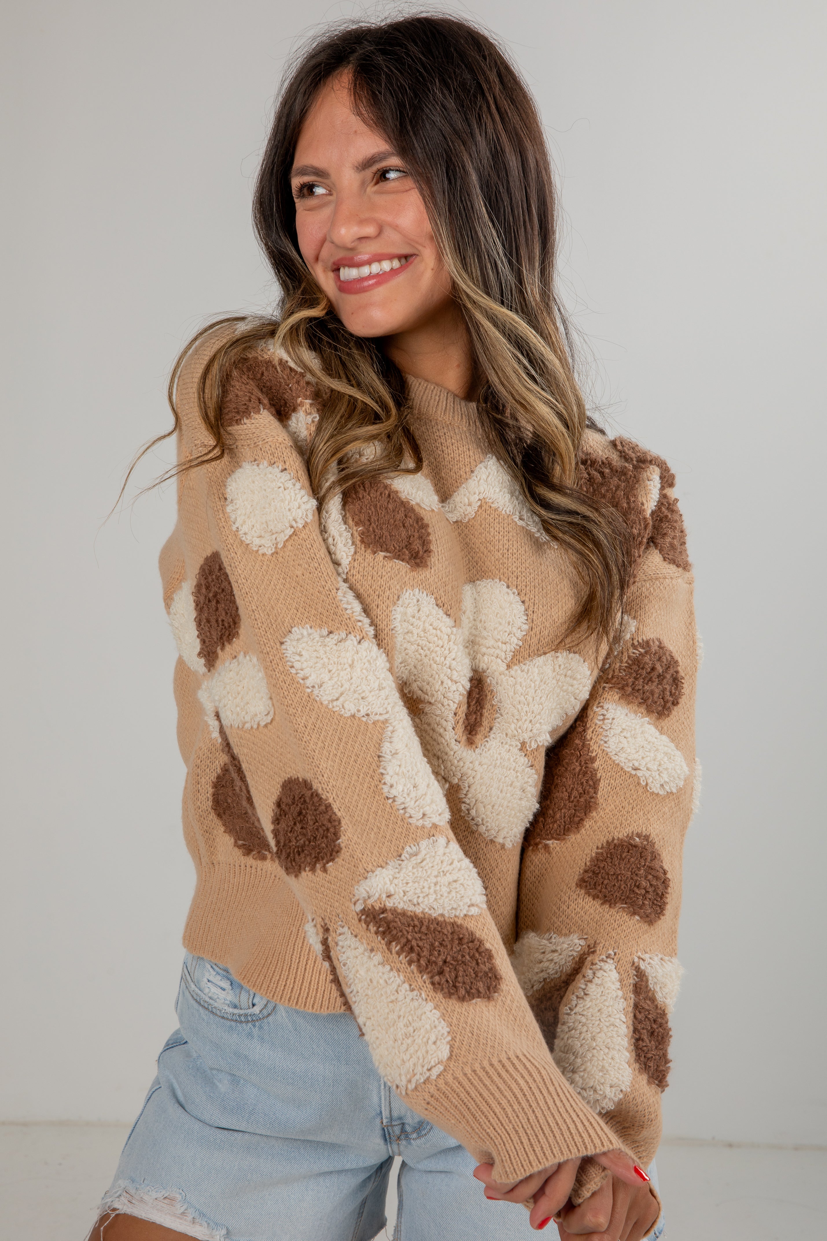 Woman wearing a patterned beige sweater with a plain background