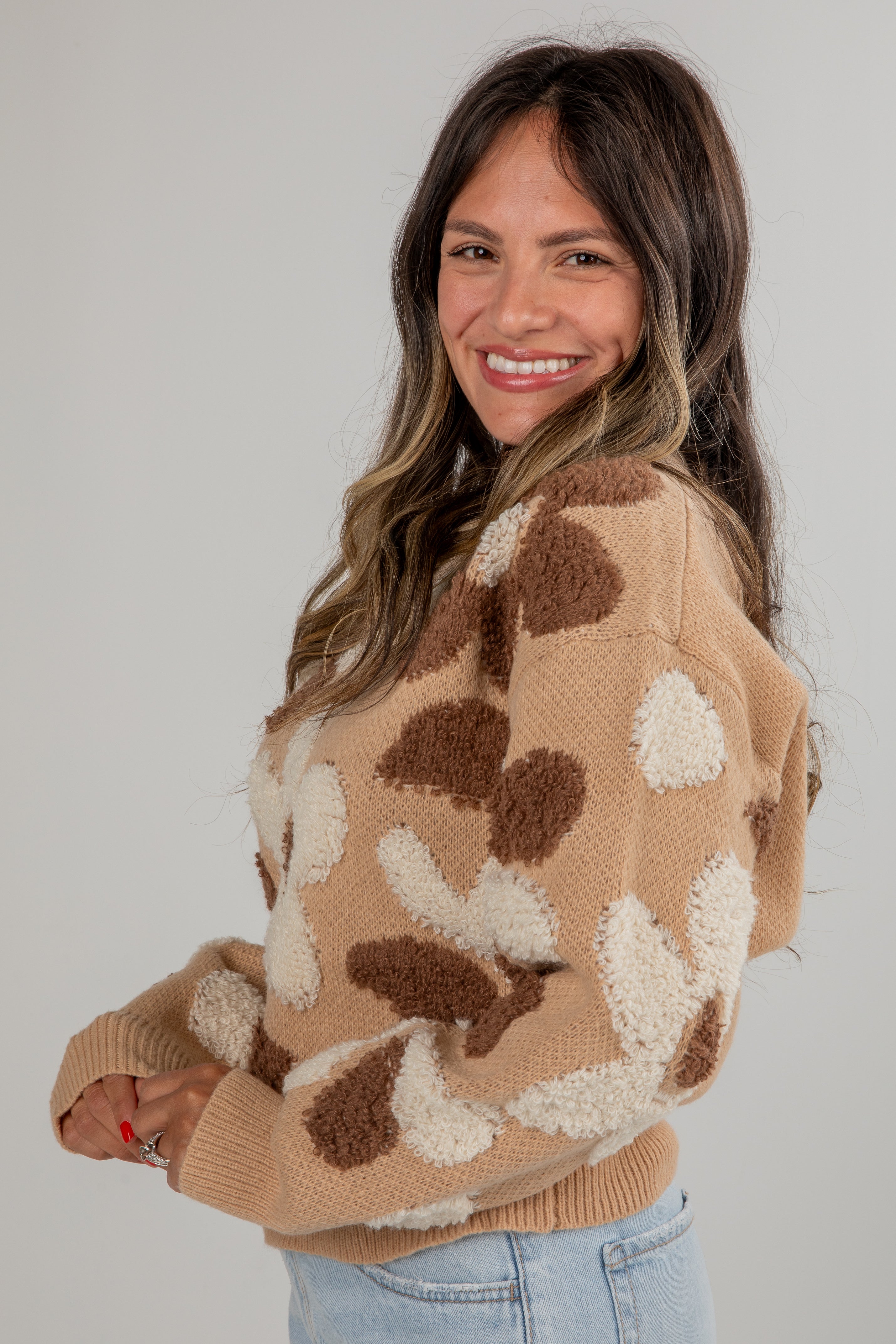 Woman wearing a beige sweater with brown and white pattern against a plain background